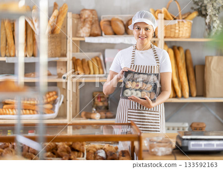 Saleswoman in work uniform holding a box of cookies Saleswoman in work uniform holding a box of cookies 133592163