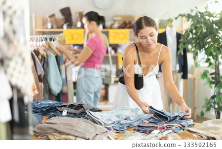 Search and selection of new jeans or shorts in a clothing store for young woman 133592165