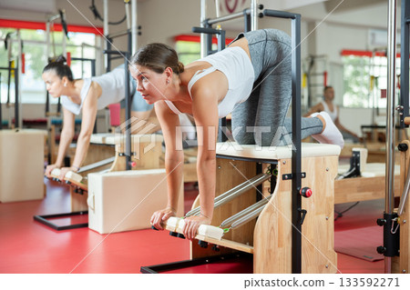 Young girl doing exercises standing on knees on combo chair 133592271