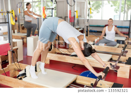 Young girl doing full body exercises lying on reformer device 133592321