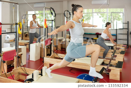 Young woman doing stretching on pilates machine Young woman doing stretching on pilates machine 133592334