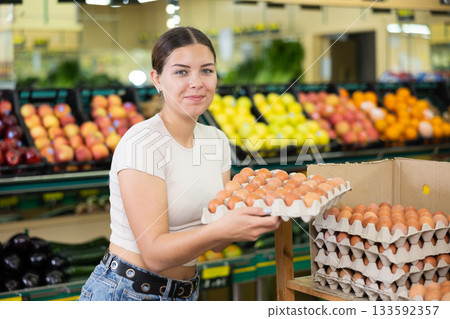 Young lady in supermarket buys chicken eggs. Young lady in supermarket buys chicken eggs. 133592357