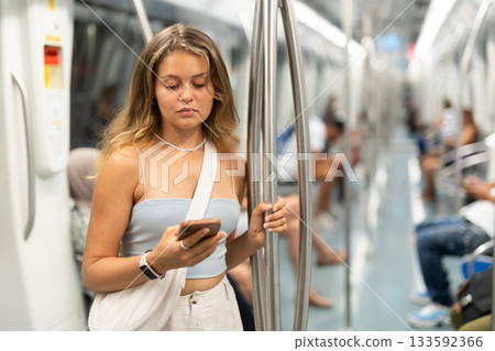 Young girl standing in wagon holding phone in hand 133592366