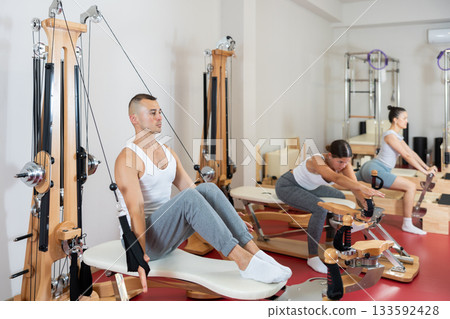 Young man training his arms using straps 133592428