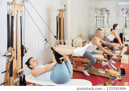 Active young woman doing press exercises on cable training device 133592494