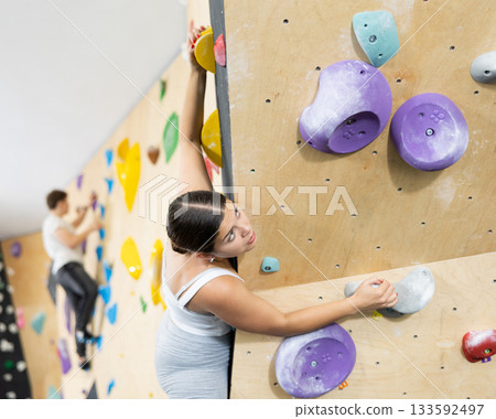 Woman training at bouldering gym without special climbing equipment Woman training at bouldering gym without special climbing equipment 133592497