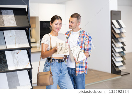 Married couple discussing the color of ceramic tiles for the bathroom in hardware store Married couple discussing the color of ceramic tiles for the bathroom in hardware store 133592524