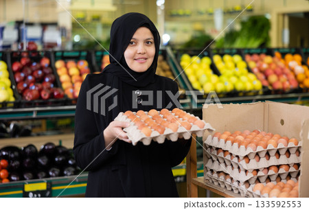 Young woman in hijab buys eggs in grocery store 133592553