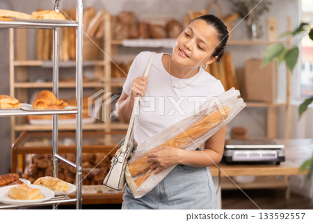 Asian woman holding a baguette in her hands 133592557