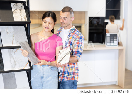 Husband and wife discussing the color of ceramic tiles for the bathroom in hardware store 133592596