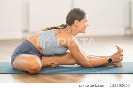 Lover of active lifestyle on yoga mat perform doing Parivritta Janu Shirshasana in gym Lover of active lifestyle on yoga mat perform doing Parivritta Janu Shirshasana in gym 133592603