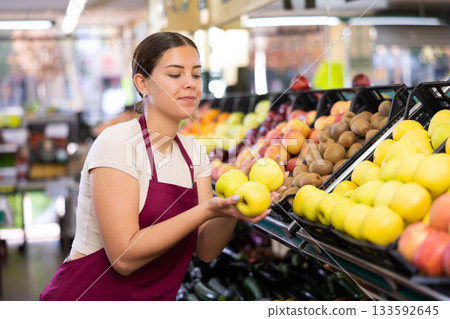 Young woman seller lays out apples in supermarket 133592645