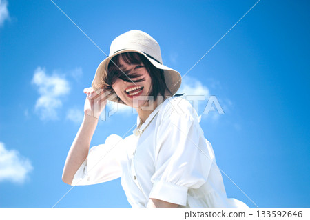 A smiling woman wearing a hat under the blue sky 133592646