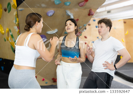 Asian girl, European woman and teenage guy - group of friends stand actively relaxing in climb hall Asian girl, European woman and teenage guy - group of friends stand actively relaxing in climb hall 133592647