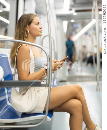 Young girl sitting in wagon holding mobile phone in hand 133592651
