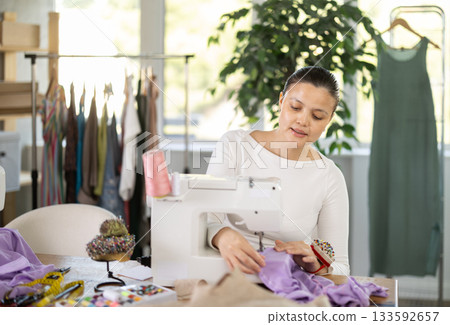 Asian woman sewing on a sewing machine in a workshop Asian woman sewing on a sewing machine in a workshop 133592657