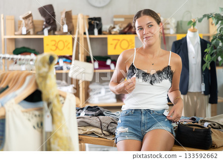 Positive joyful woman looking for fashionable clothes in clothing boutique Positive joyful woman looking for fashionable clothes in clothing boutique 133592662