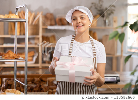 Saleswoman holding a box with a bow Saleswoman holding a box with a bow 133592666
