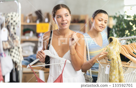 Girl customer choose something clothing for summer. Female client looking for clothes in background Girl customer choose something clothing for summer. Female client looking for clothes in background 133592701