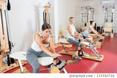Young woman stretching her arms using pilates machine 133592710