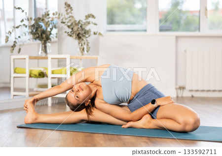 Sportive girl practicing head to knee pose of yoga in light room 133592711