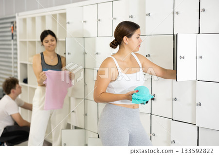 Young europian girl stands in locker room of gym and takes out necessary clothes for training. Young europian girl stands in locker room of gym and takes out necessary clothes for training. 133592822