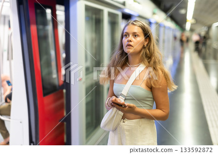 Young woman with phone stands at metro station Young woman with phone stands at metro station 133592872