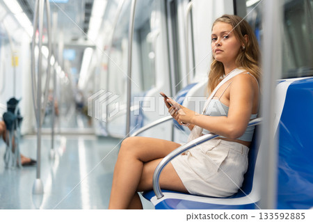 Young woman sitting in subway car with phone Young woman sitting in subway car with phone 133592885