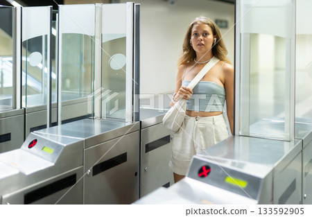 Female passenger enters underground metro station through control area, checkpoint. 133592905