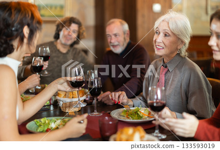 Large friendly family gathered at table to have lunch in restaurant 133593019