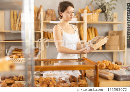 Girl in casual clothes chooses fresh cookie for breakfast in bakery Girl in casual clothes chooses fresh cookie for breakfast in bakery 133593072