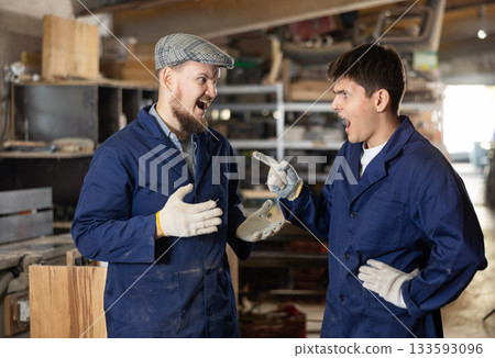Young male carpenters quarreling in workshop 133593096