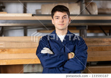 Young guy carpenter posing in wood workshop Young guy carpenter posing in wood workshop 133593187