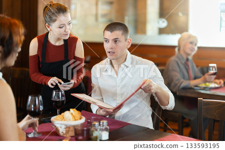 Young waitress taking order from young couple in restaurant Young waitress taking order from young couple in restaurant 133593195