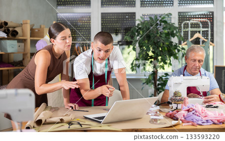 woman with a team of tailors designing clothes in a workshop 133593220