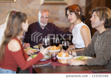 Family members enjoying warm conversation in restaurant 133593389