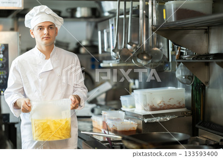 Young male cook carrying potato slices in container Young male cook carrying potato slices in container 133593400