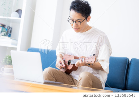 A man taking online musical instrument (ukulele) lessons 133593545