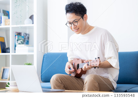 A man taking online musical instrument (ukulele) lessons 133593548