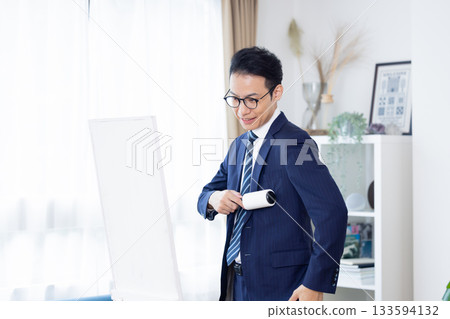 A middle-aged man removes dirt from his suit with a sticky cleaner in the morning A middle-aged man removes dirt from his suit with a sticky cleaner in the morning 133594132