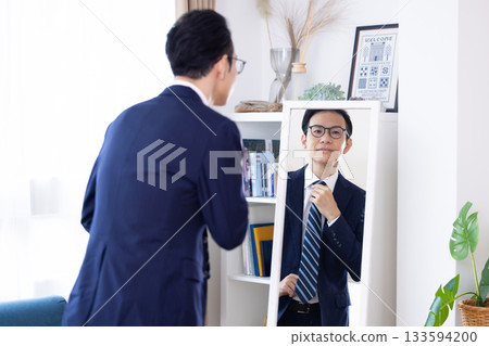 A middle-aged man getting ready in the morning while looking in the mirror 133594200