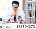 A man eating while looking at his smartphone before going to work 133594272