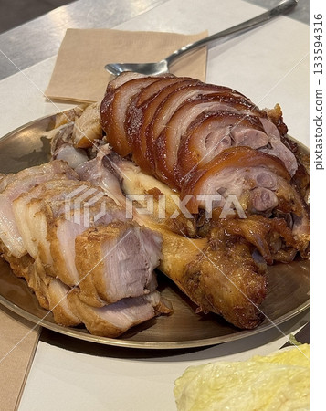 Tenderly sliced jokbal with glossy, rich brown skin beside neatly arranged suyuk slices, showing soft texture, juicy layers of meat, and appetizing contrast on a clean serving plate in detail 133594316