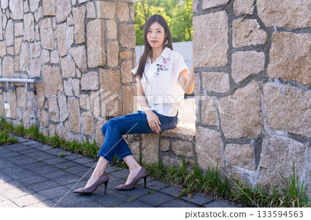 Woman sitting on a concrete wall Woman sitting on a concrete wall 133594563
