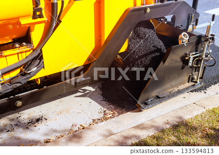 Fresh asphalt is being laid by road construction paving machine on urban development. 133594813