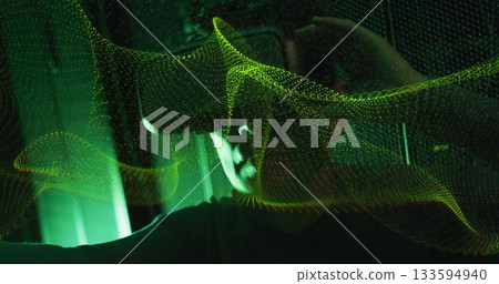 Asian man wearing VR headset exploring holographic wave in VR lab, with LED panels 133594940