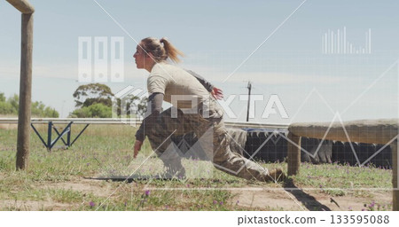 Crawling female soldier navigating beneath wooden beam obstacle in training ground, with red gloves 133595088