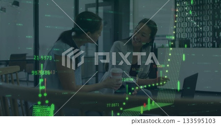 Two coworkers in business attire chatting in lounge, with coffee cups, laptop and financial chart Two coworkers in business attire chatting in lounge, with coffee cups, laptop and financial chart 133595103