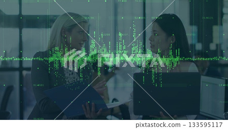 Coworkers discussing analytics data overlay at modern open-plan office, with blue folder and laptop 133595117