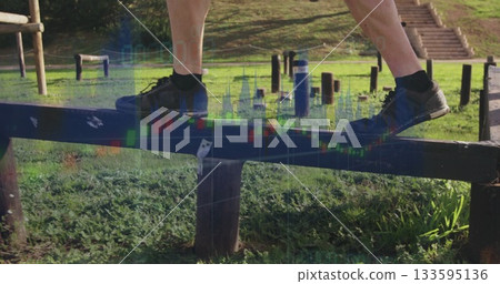 Balancing male wearing black socks, athletic shoes on wooden beam in grassy park, with stone steps 133595136